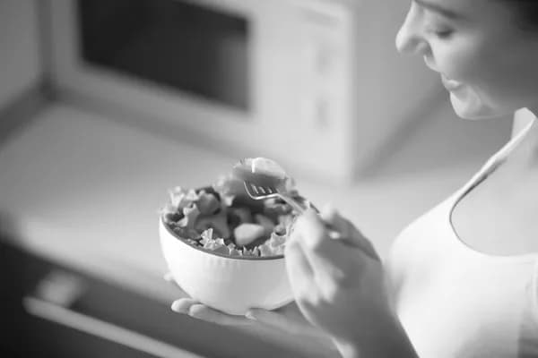 A woman eating salad from a bowl.